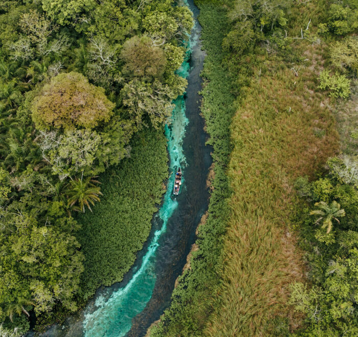 Vue aérienne d’une rivière à Bonito au Brésil avec une pirogue naviguant au milieu des eaux cristallines.